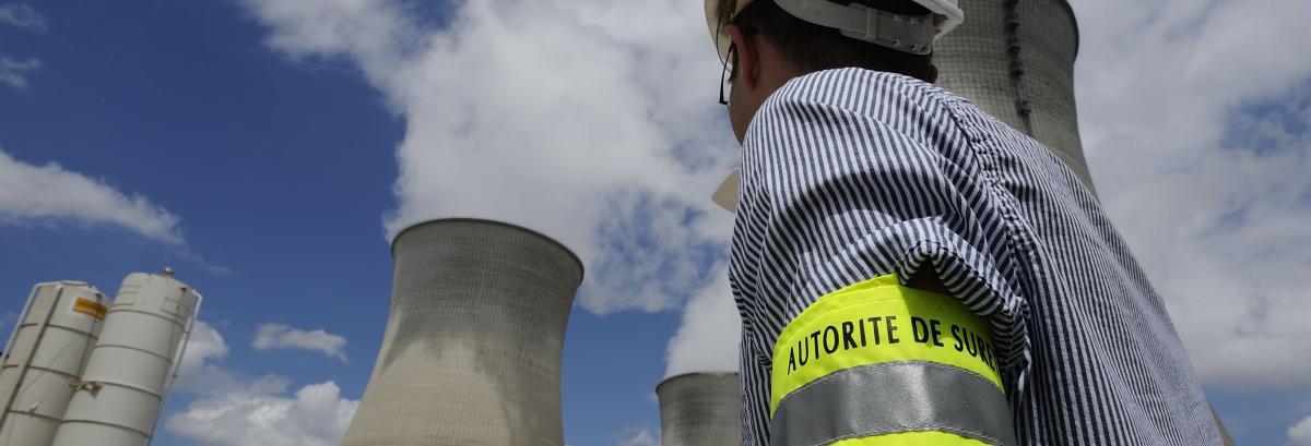 Photo d’une personne de l’Autorité de sûreté nucléaire devant une centrale nucléaire.